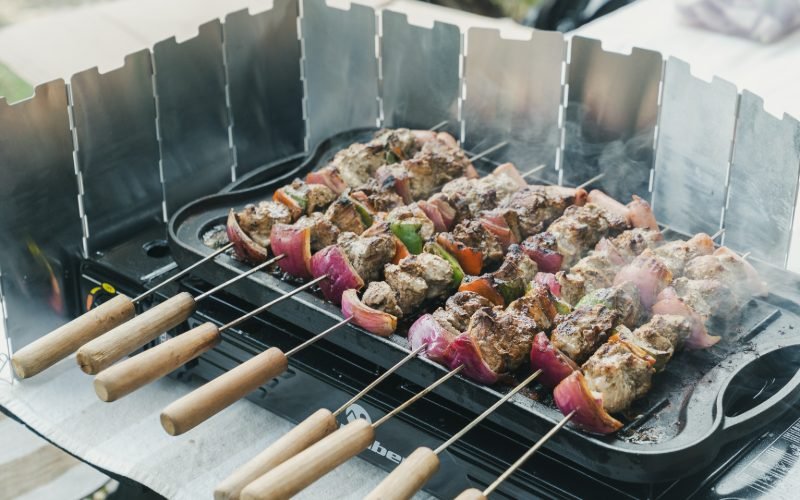 Anticuchos cooking on a gas grill beside the river in the Andes