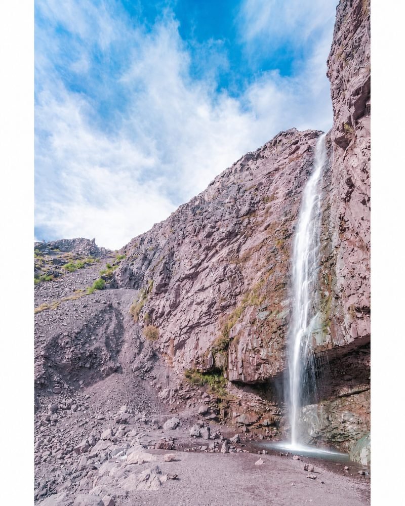 Tall waterfall cascading down volcanic rock walls in Cajón del Maipo