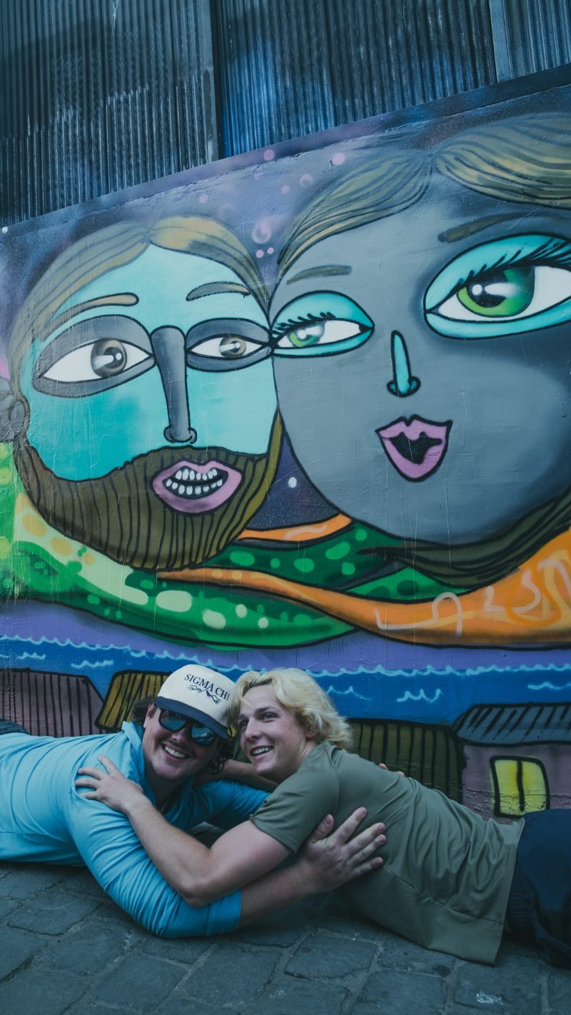 Two travelers playfully posing in front of a vivid street art mural in Valparaíso