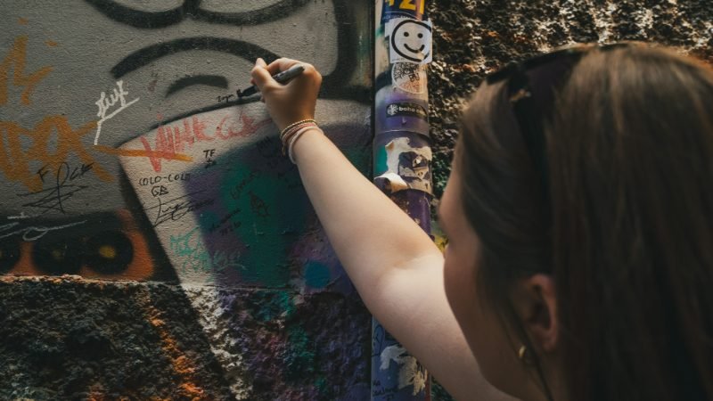 Traveler adding her own mark to a graffiti wall in Valparaíso's cerros