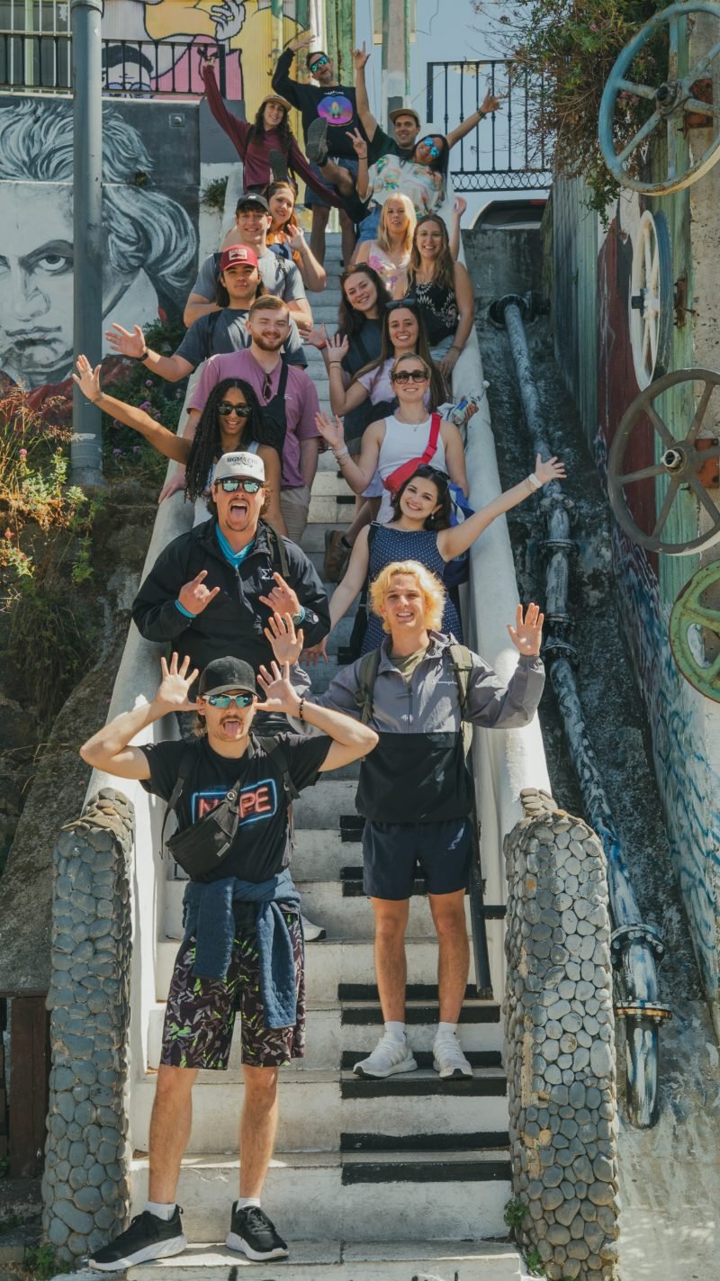 Full group posing on Valparaíso's iconic painted staircase surrounded by murals
