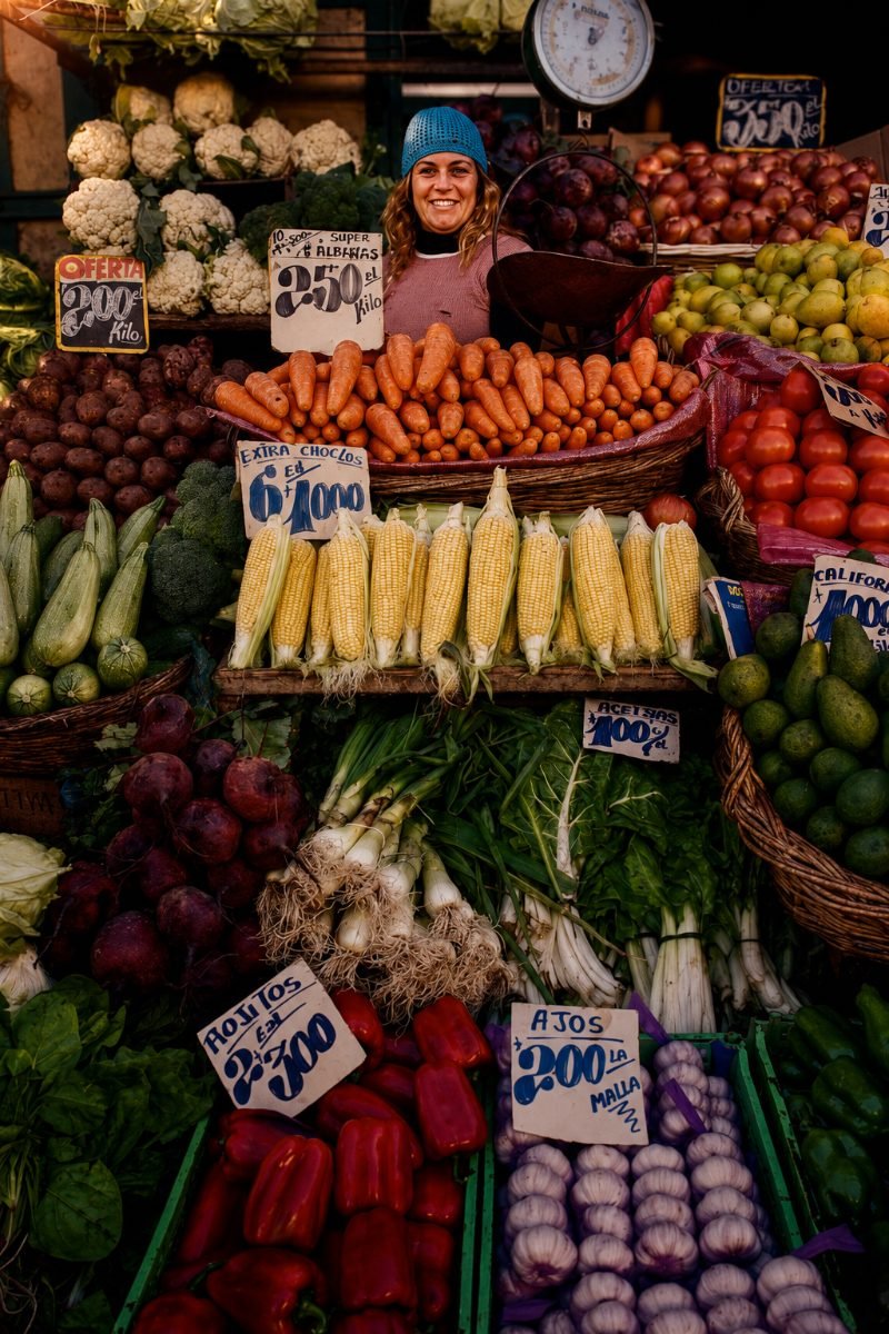 Mujer sonriendo en su puesto de verduras en el mercado de Santiago